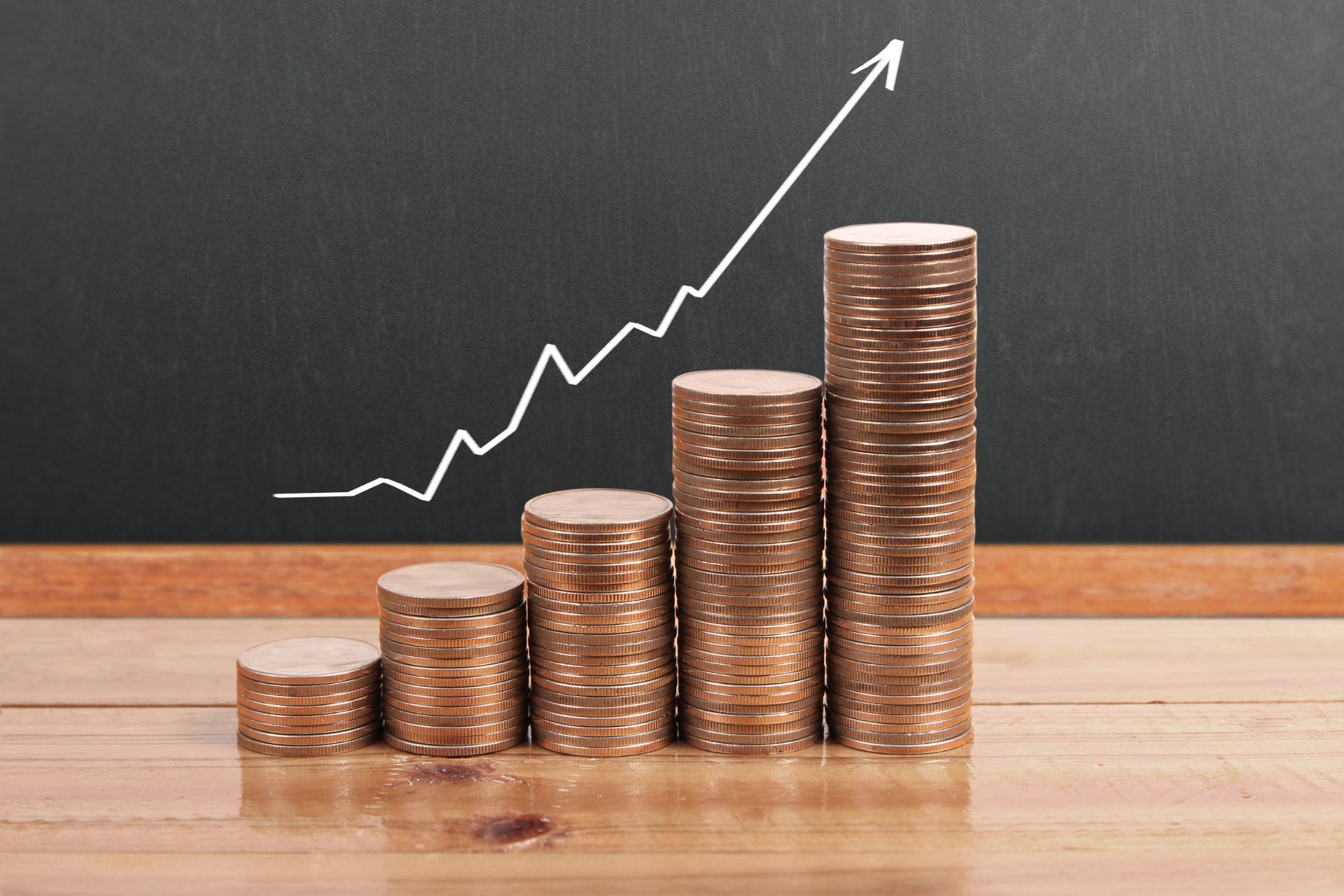 Five stacks of coins progressively getting tallers with an upward graph behind - Guide to staking plans featured image